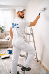 Malíř nanáší barvu na stěnu bytu – Malíři Ostrava